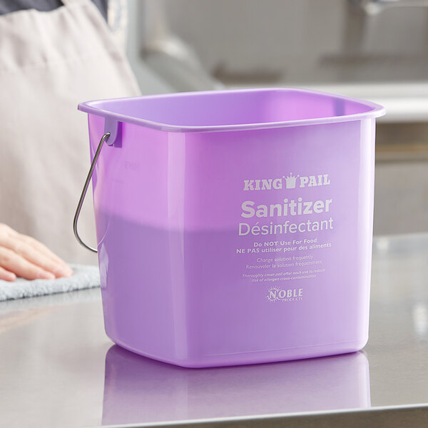 A close-up of a Noble Products purple sanitizing pail with a handle.