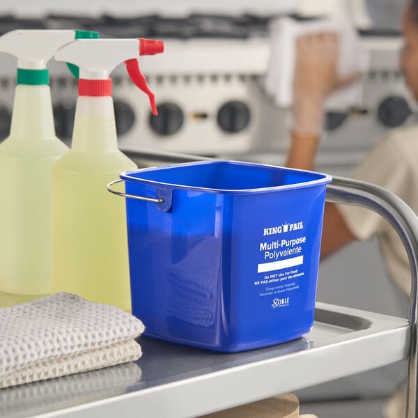 A blue 3-quart cleaning pail labeled 'Noble King-Pail Multi-Purpose' on a cleaning cart.