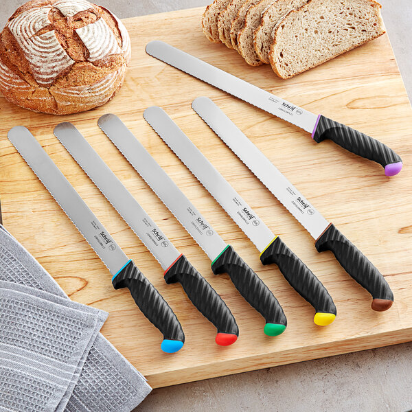 A Schraf serrated slicing knife with a purple handle next to a loaf of bread.