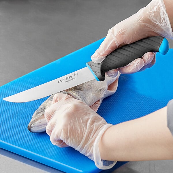 A person in gloves using a Schraf utility knife with a blue TPRgrip handle to cut fish on a blue cutting board.