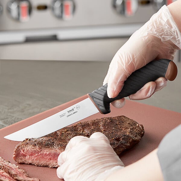 a person wearing gloves and holding a piece of meat