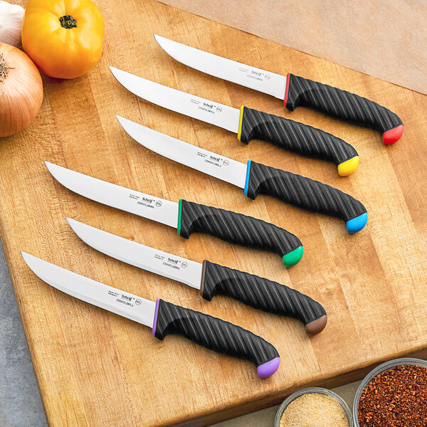 A Schraf utility knife with a black handle on a table with a group of knives.