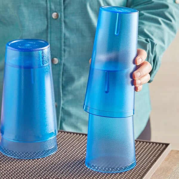 A woman holding a blue plastic Choice tumbler.