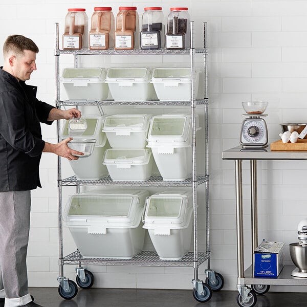 A man standing in front of a white shelf with white Baker's Lane ingredient bins with clear flip lids.