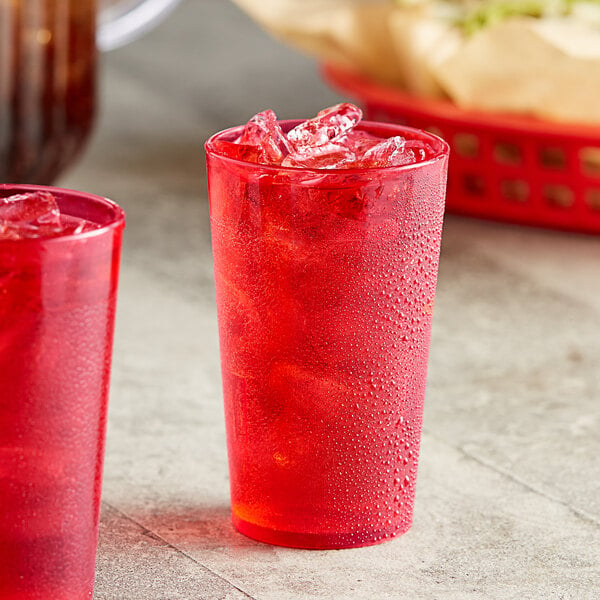 Two red Choice plastic tumblers filled with a red drink on a table.