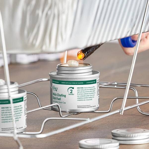A can of Choice 2 Hour Wick Chafing Dish Fuel with a safety twist cap being lit under a chafing dish rack.