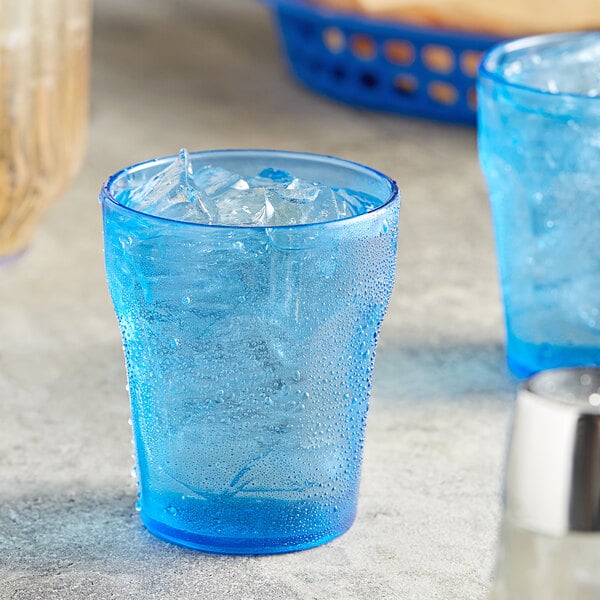 A blue plastic tumbler with ice and a straw.