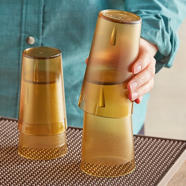 A person holding two Choice amber plastic tumblers.
