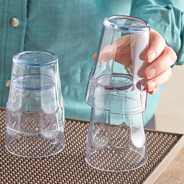 A woman's hand holding a clear Choice plastic tumbler.