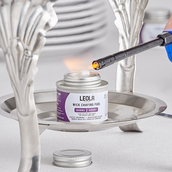 A hand using a lighter to ignite Leola Fuel chafing dish fuel with a safety twist cap.