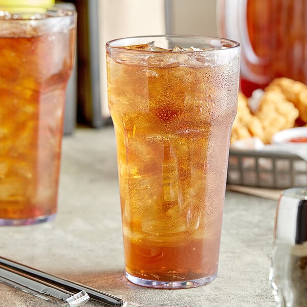 Two Choice clear plastic tumblers filled with ice tea on a table.