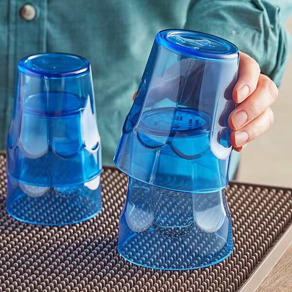 A person holding two blue Choice plastic tumblers full of blue liquid.