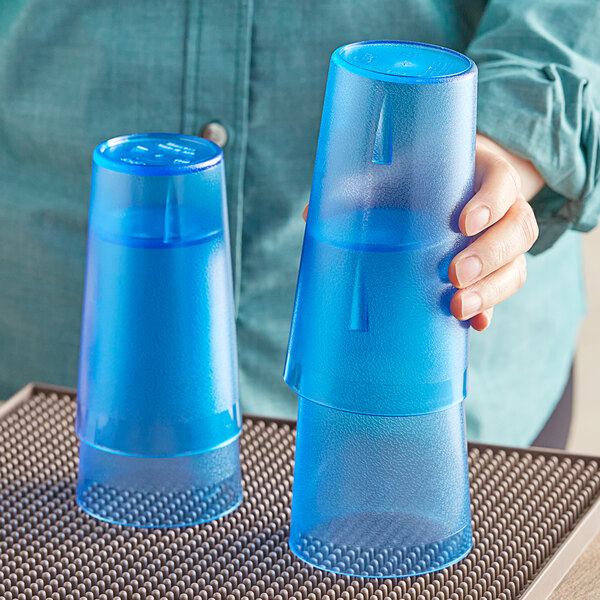 A woman holding a pair of blue Choice plastic tumblers.