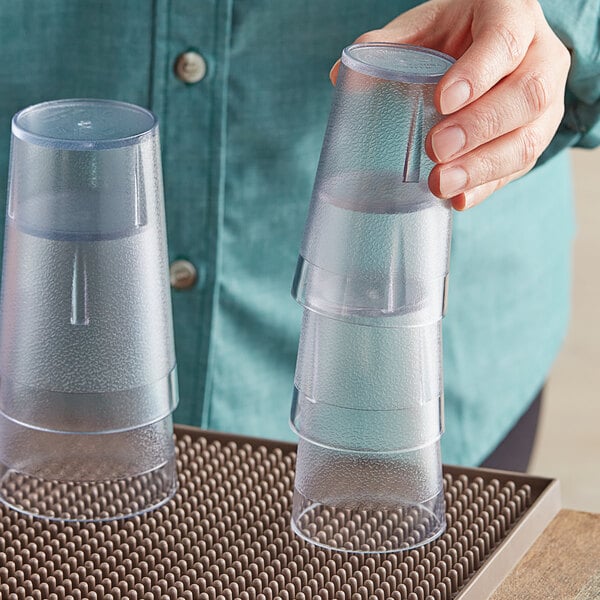 A person holding a stack of clear plastic Choice tumblers.