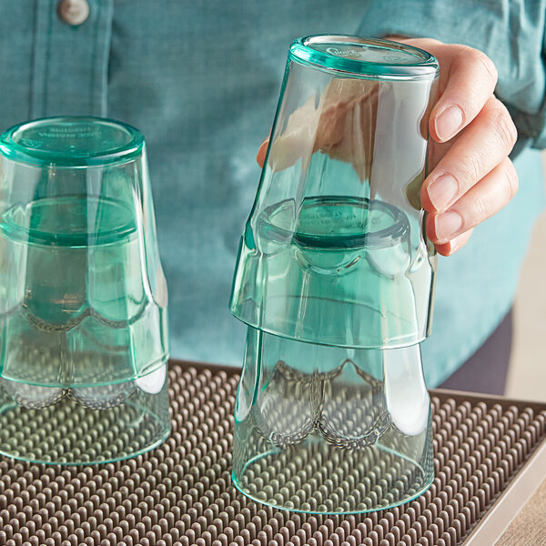 A person holding a stack of Choice green plastic paneled tumblers.