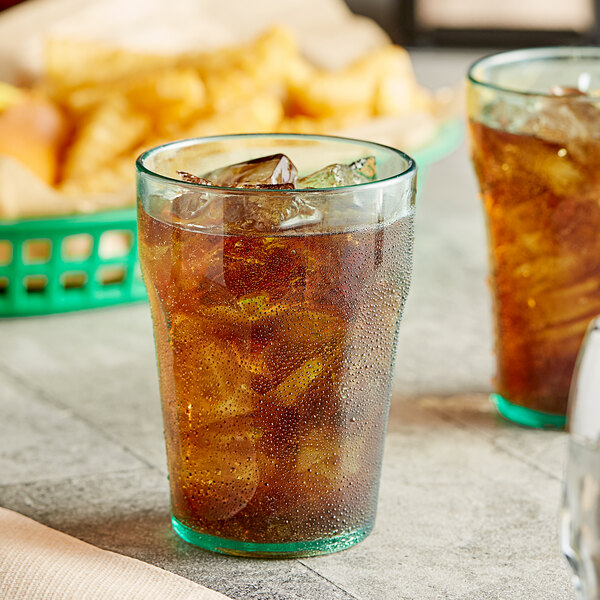 Two Choice green plastic paneled tumblers filled with brown liquid on a table.