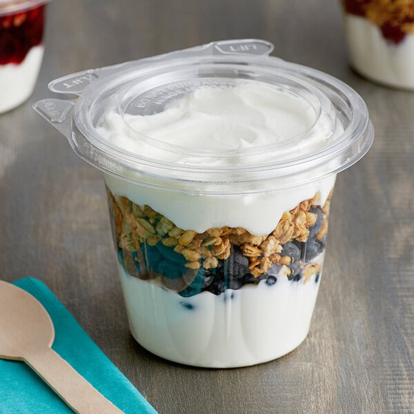 A Dart plastic snack cup with yogurt and granola with a flat lid.