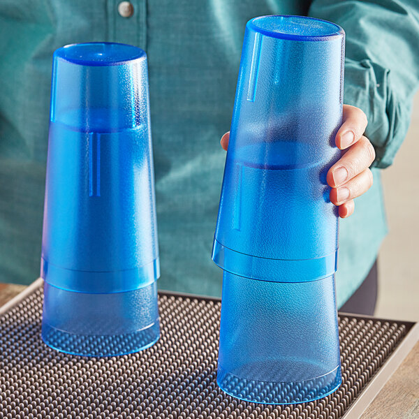 A person holding two blue Choice plastic tumblers.
