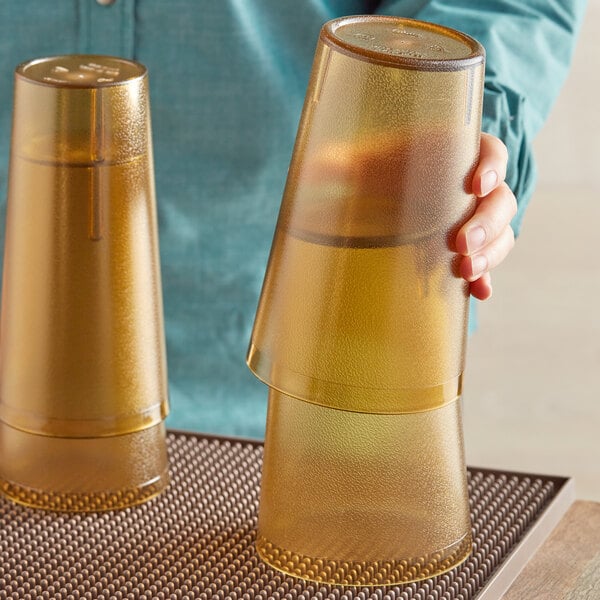 A woman holding a pair of Choice plastic tumblers on a table.