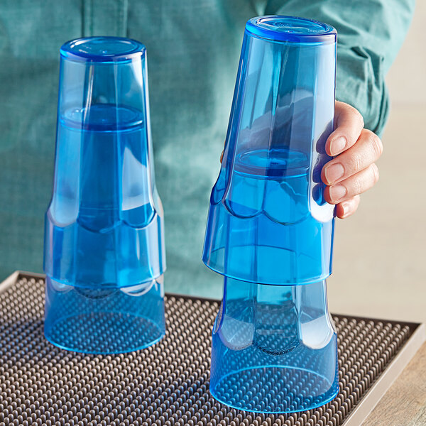 A person holding a pair of Choice blue plastic cups.