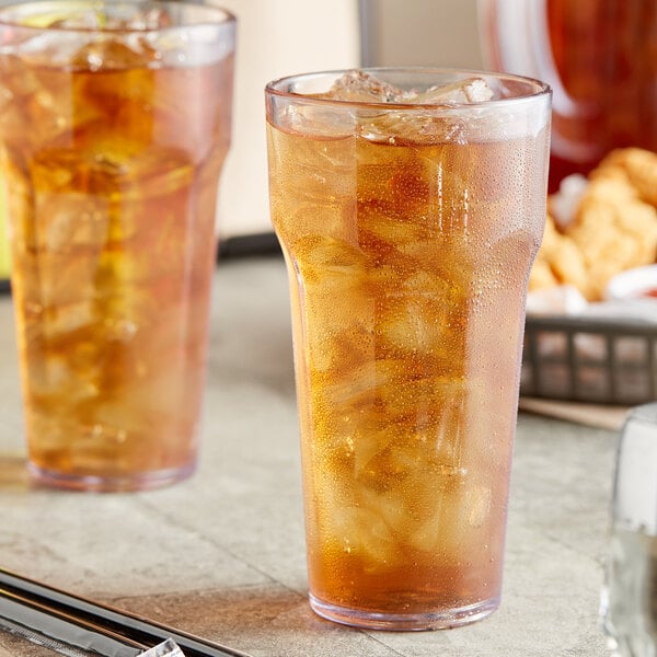 Two Choice clear plastic tumblers filled with ice tea on a table.