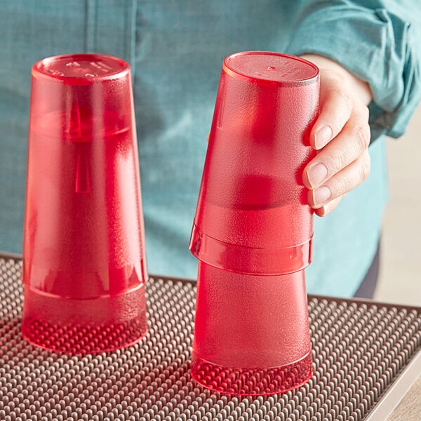 A person holding a red Choice plastic tumbler filled with red liquid.