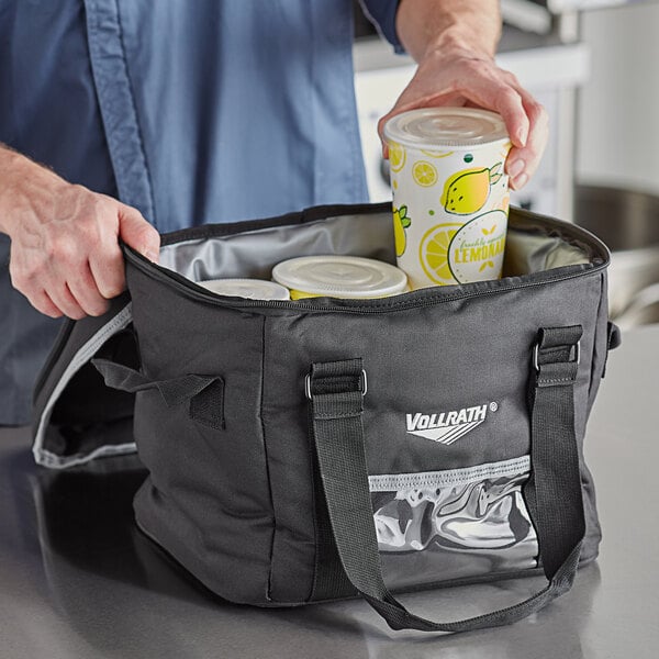 A man holding a Vollrath small insulated cooler bag with drinks.