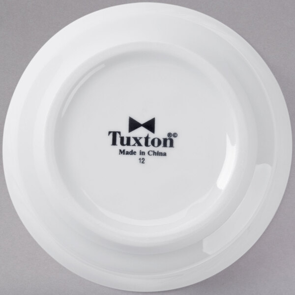 A Tuxton bright white china bowl with an embossed rim and black Tuxton text.