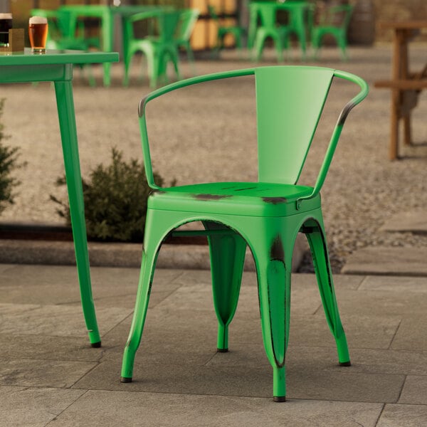 A Lancaster Table & Seating distressed jade green outdoor arm chair on a stone surface.