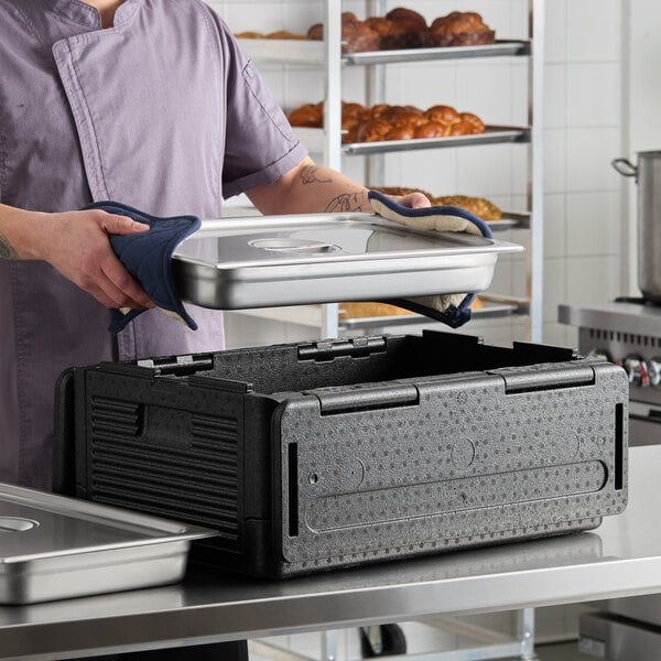 A black insulated food pan carrier with two full-size stainless steel food pans and lids, designed for keeping food hot or cold during transport.