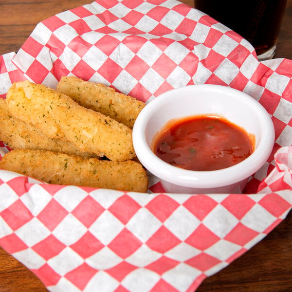 A basket of fried fish sticks with a cup of red sauce.