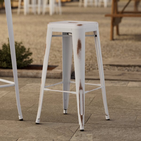 A Lancaster Table & Seating distressed pearl white outdoor barstool.