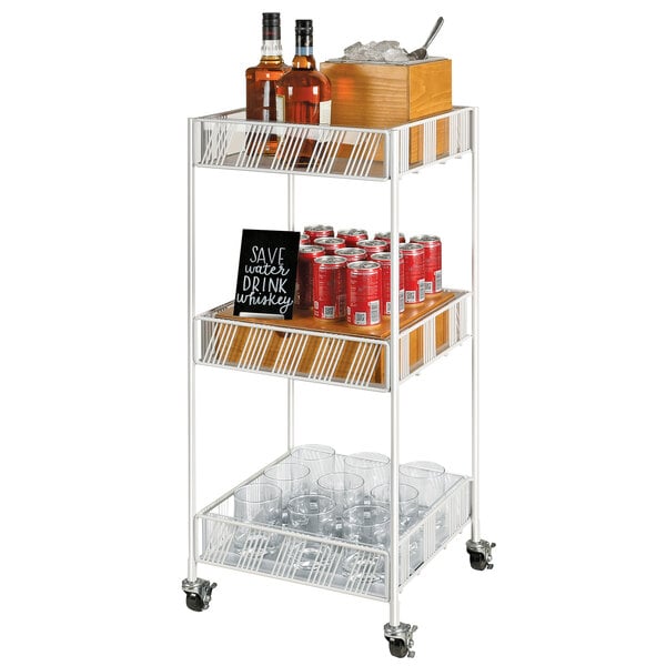 A white metal Cal-Mil Portland merchandiser cart with plastic inserts holding bottles and glasses.