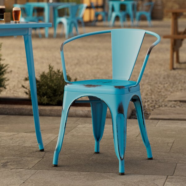 A blue Lancaster Table & Seating outdoor arm chair on a stone surface.