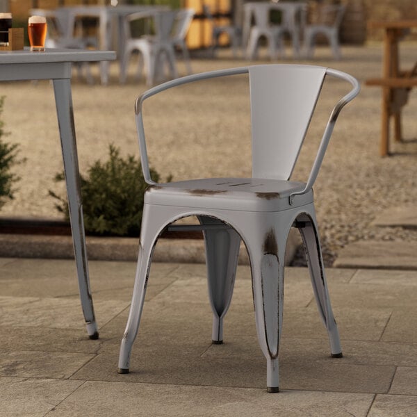 A Lancaster Table & Seating metal chair and table on an outdoor patio.