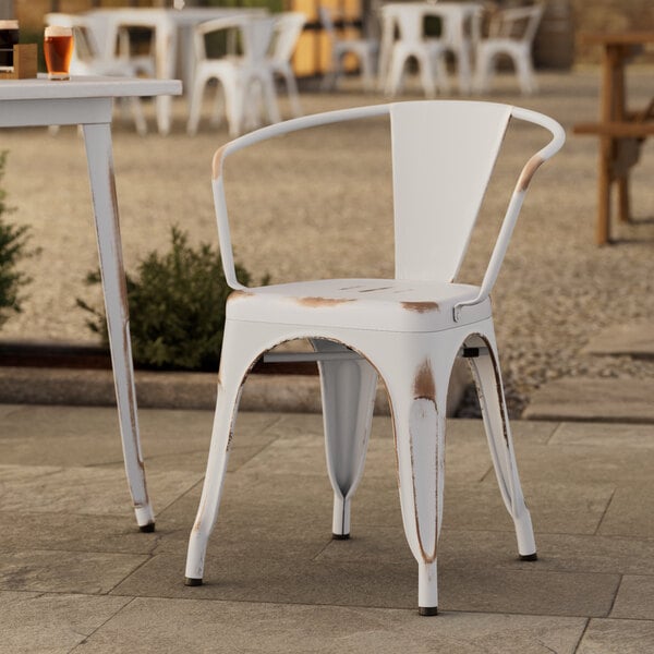 A Lancaster Table & Seating distressed white outdoor arm chair on a patio.