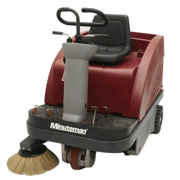 A red and black Minuteman floor sweeper with a round brush.