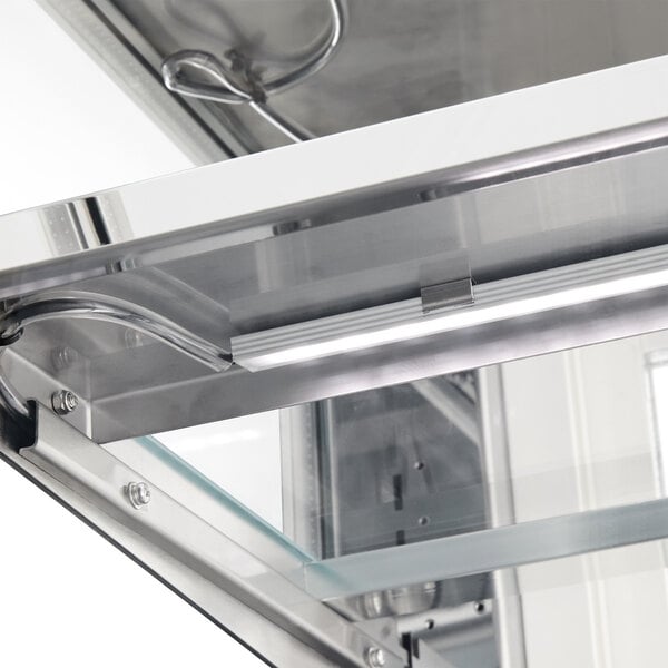 A close-up of a white metal frame with glass shelves inside an Avantco refrigerated bakery display case.