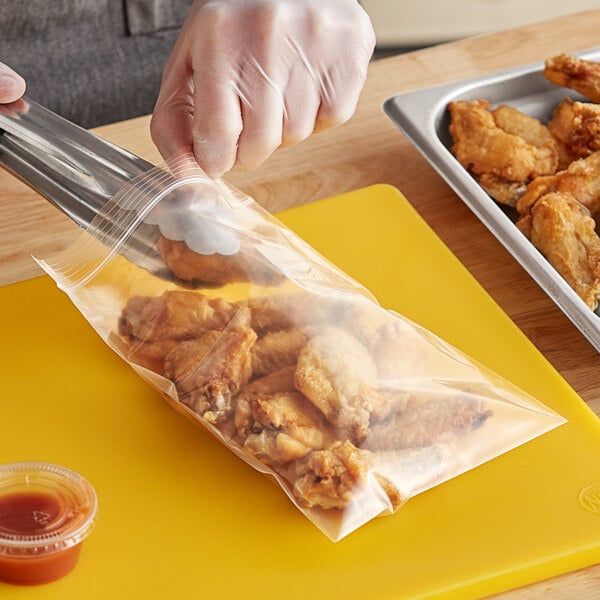 A person putting chicken in a Choice clear plastic bag.