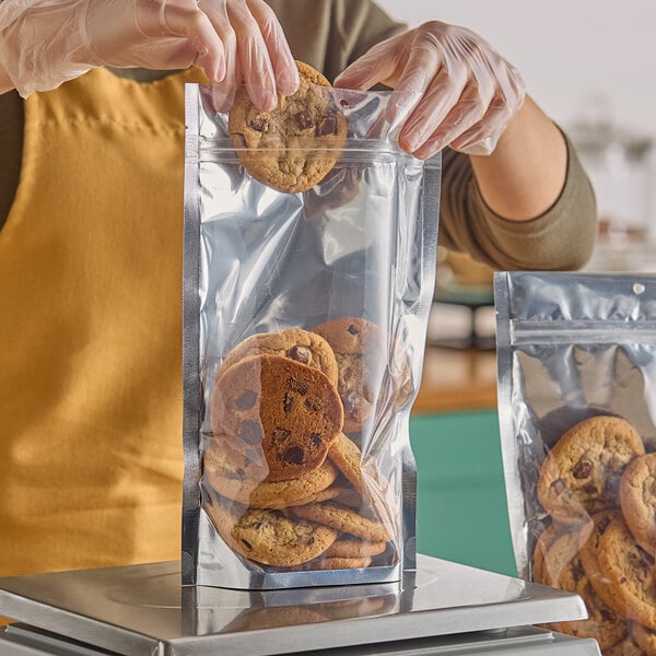 A person putting a cookie in a Choice clear plastic zip top pouch.