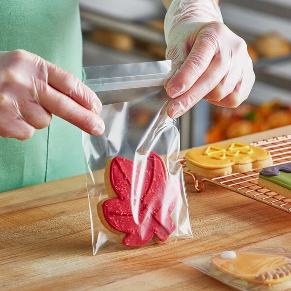 A person in a green shirt using a Choice plastic bag to put a cookie on a table.