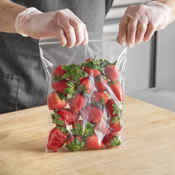 A person in gloves holding a Choice clear plastic bag of strawberries.