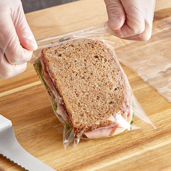 A person's hand holding a sandwich in a Choice resealable plastic bag.