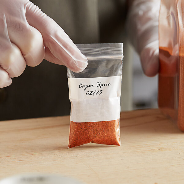 A person wearing gloves holding a Choice clear plastic bag with white block filled with spices.