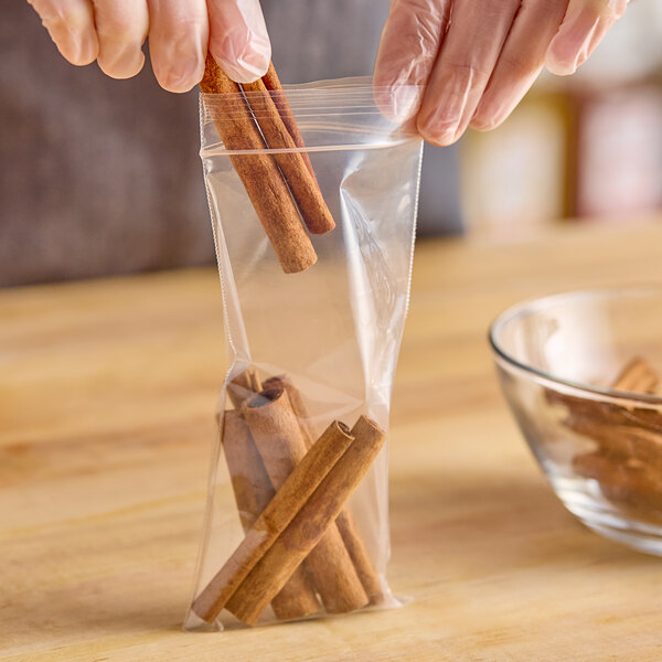 A person holding a Choice clear plastic bag of cinnamon sticks.