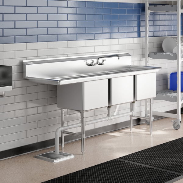 A Regency stainless steel three compartment sink with a drainboard on a counter.