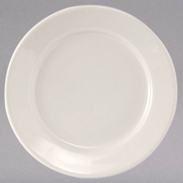 A close-up of a Tuxton Reno ivory china plate with a wide white rim.