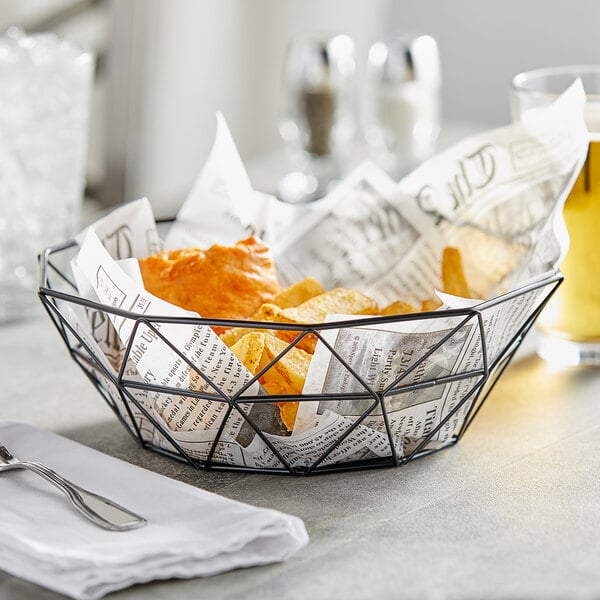 A Tablecraft black stainless steel wire serving basket of food and a glass of beer.