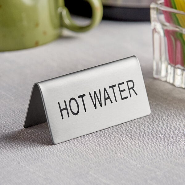 A silver stainless steel double sided "Hot Water" table tent sign on a counter.