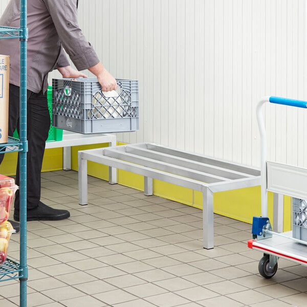 A man carrying a Regency aluminum dunnage rack.